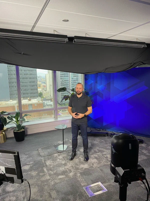 Mario Thomas standing on a video studio set in Sydney with a blue backdrop